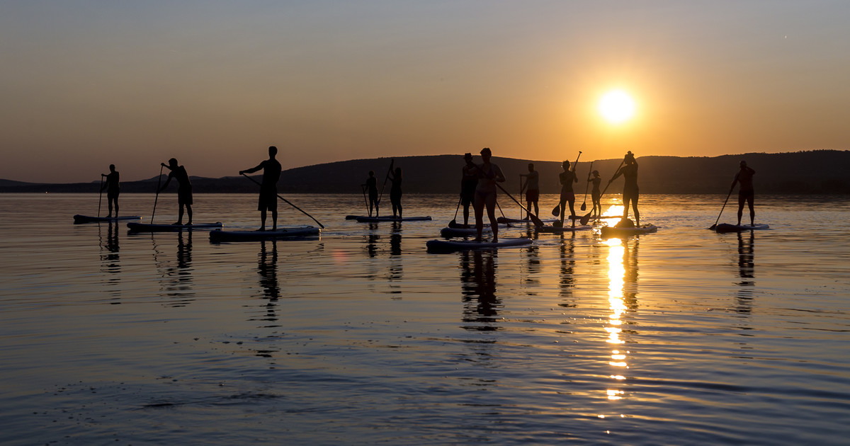 Group of paddleboarders gliding across the water at golden hour